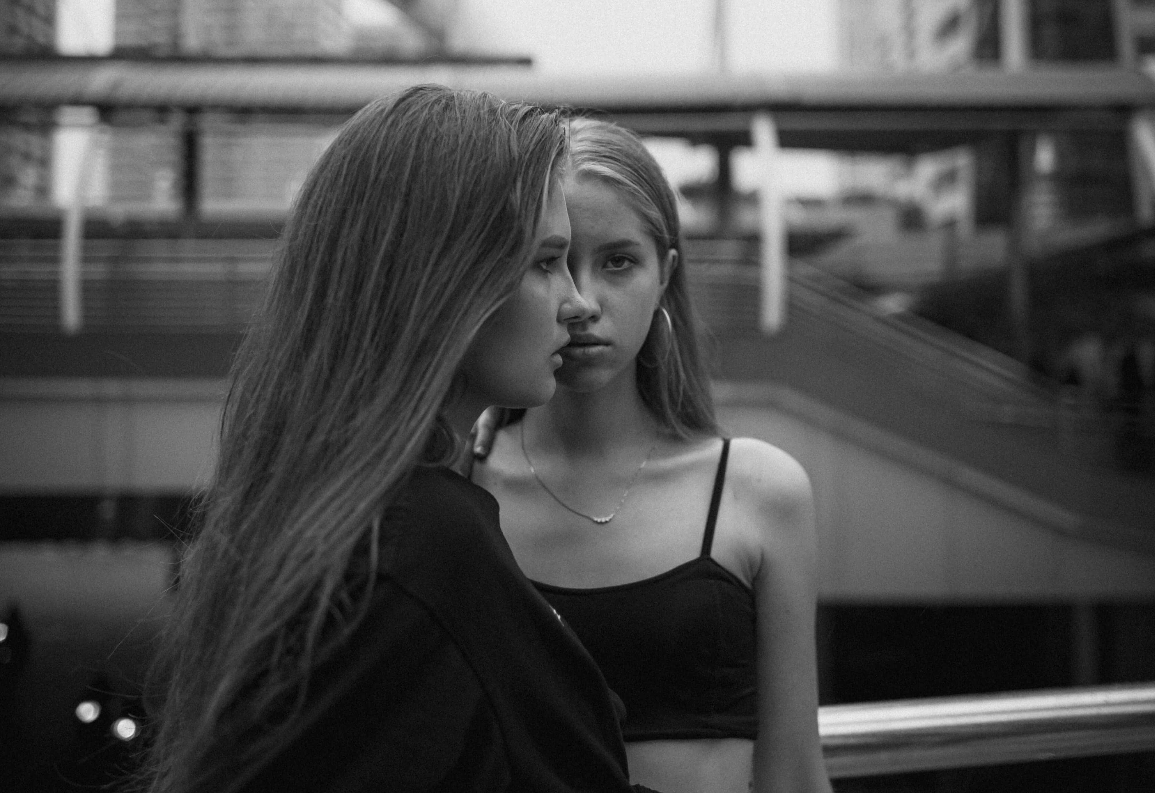 Young women standing outdoors in urban environment, black and white photo, fashion and street style inspiration.