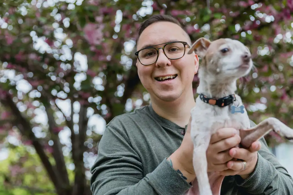 A man holding a dog, both looking content and engaged.