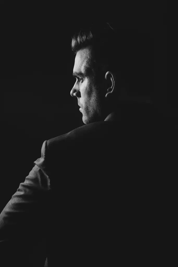 A man looks away into shadowed light